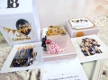 Exploding box na 18 urodziny z tortem w kolorach: jasny różowy, czarny, złoty, biały